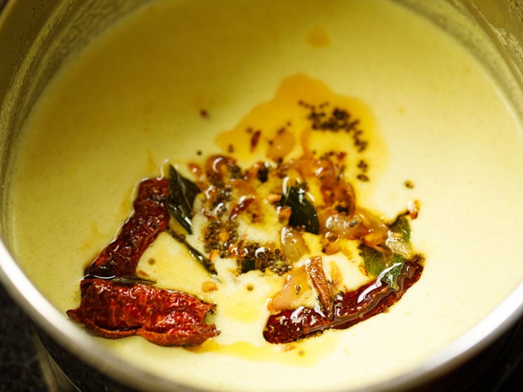 moru curry or pulissery with tadka of spices and oil added to saucepan
