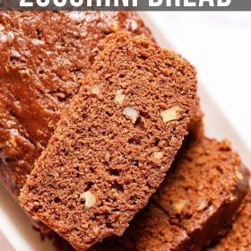 chocolate zucchini bread partly sliced with one slice kept on top of the loaf on a white rectangular tray on a white marble background