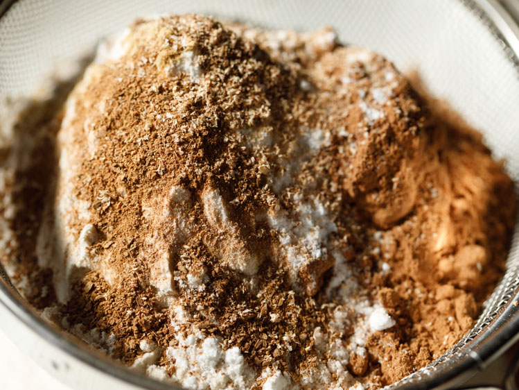 spice powders added to whole wheat flour and cocoa powder in a sieve