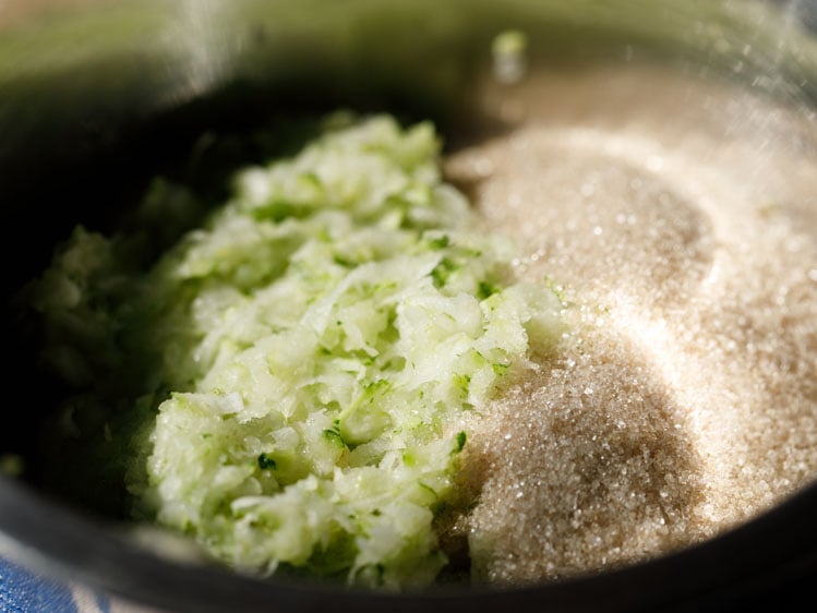 grated zucchini and raw sugar in a mixing bowl