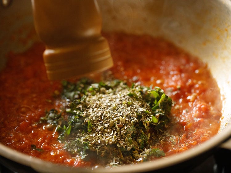 herbs added in the sauce with black pepper being crushed with a wooden mill