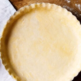 homemade all butter pie dough after rolling out and placing in a pie pan, prior to baking, with scalloped edges