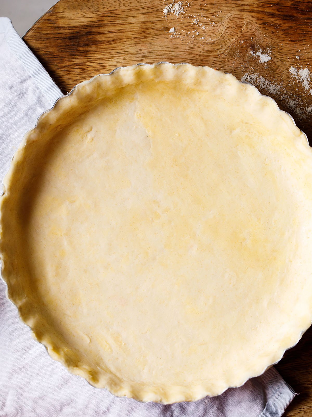 homemade all butter pie dough after rolling out and placing in a pie pan, prior to baking, with scalloped edges