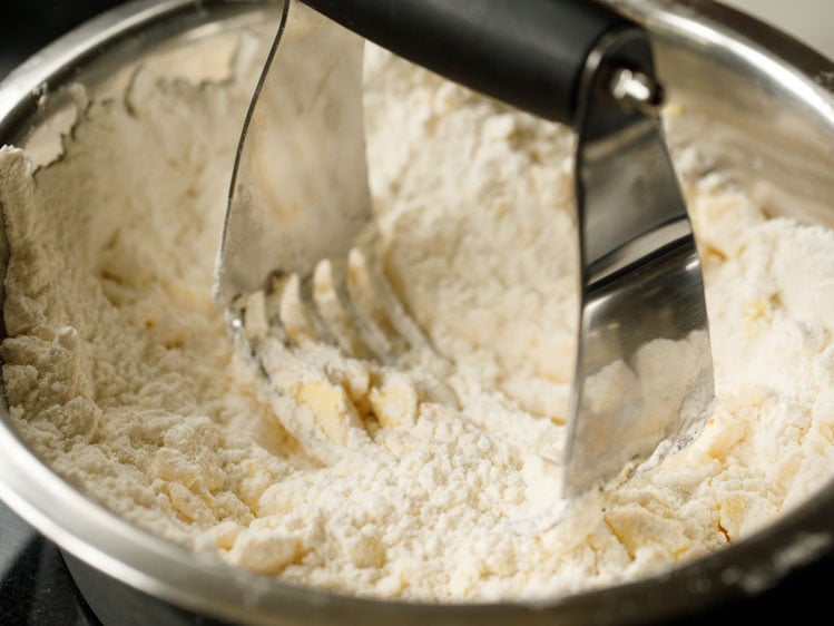 pastry cutter cutting pieces of butter into flour and salt mix