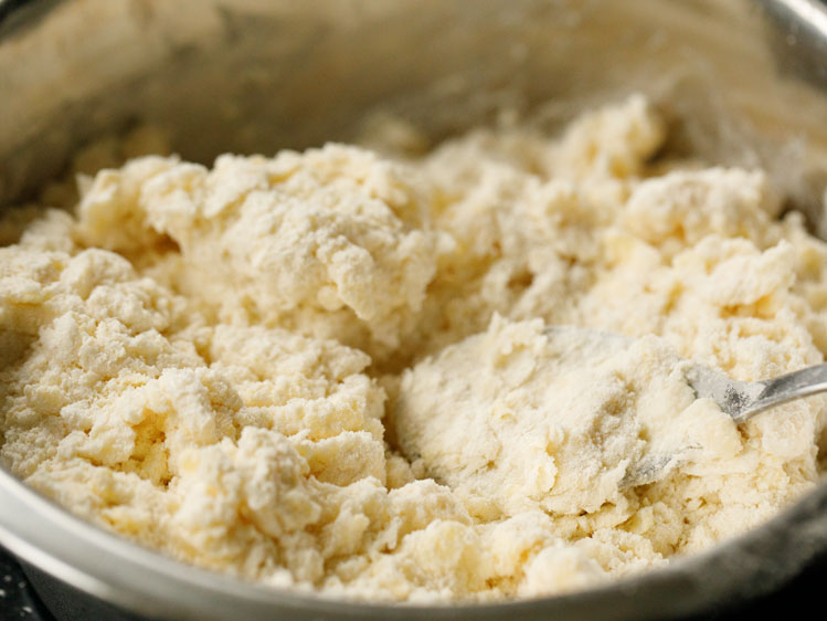 spoon in a mixing bowl with butter and flour mix for homemade pie crust recipe after first addition of water