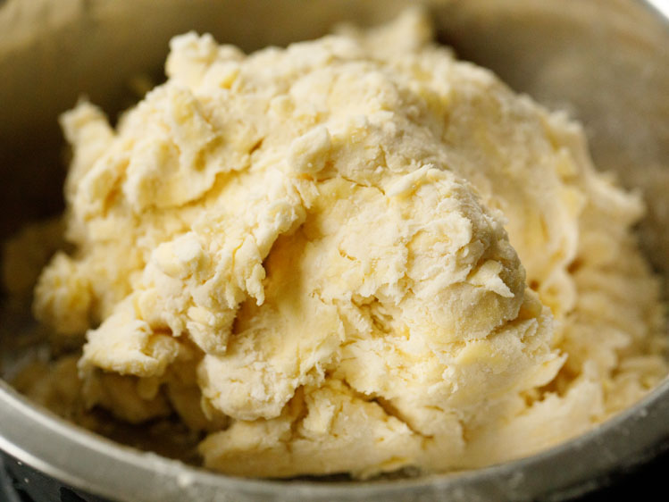 pie dough recipe in a silver bowl after it has come together with addition of cold water. crust appears craggy