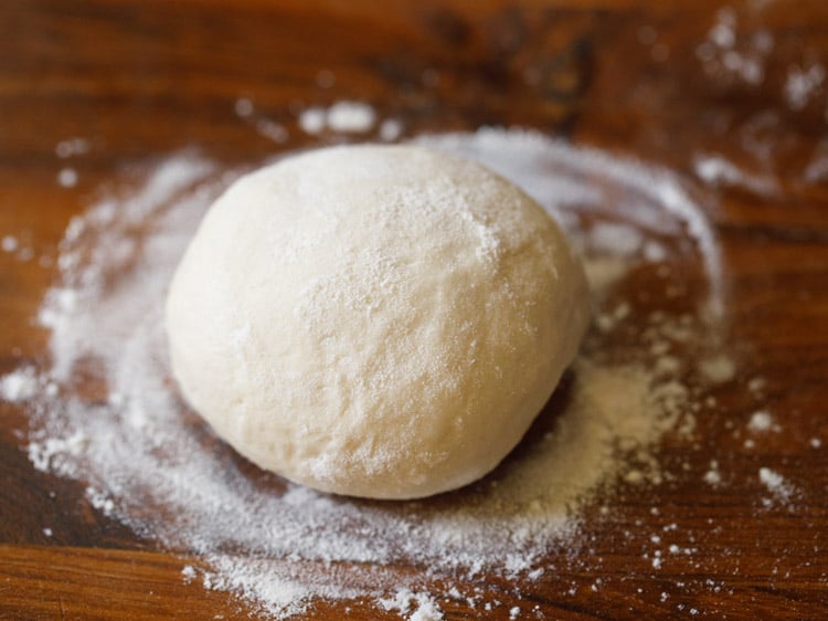 assembling-veg-pizza2 a dough ball dusted with flour on a wooden board