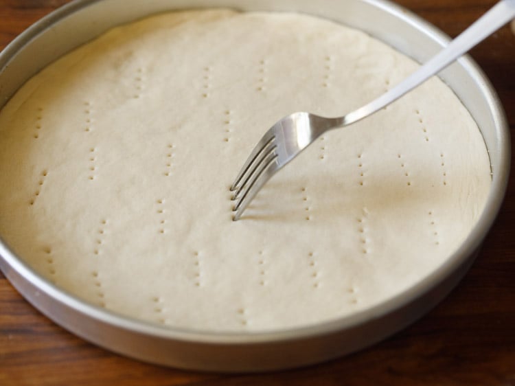 pizza dough being pricked with a fork