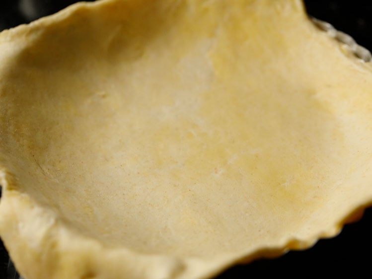 pie dough being placed in a fluted pie dish