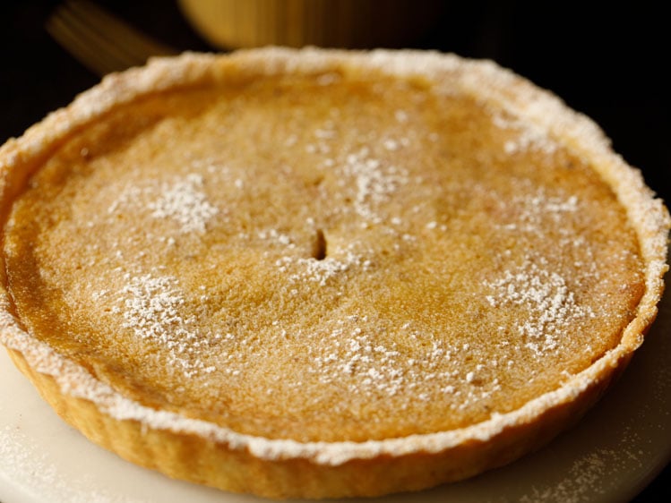 baked eggless pumpkin pie on a white serving platter dusted with confectioner's sugar