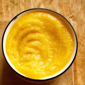 homemade pumpkin purée in a white bowl with a black rim on a light brown jute fabric