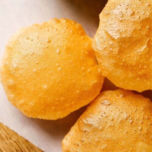 perfect golden puri placed on white parchment paper
