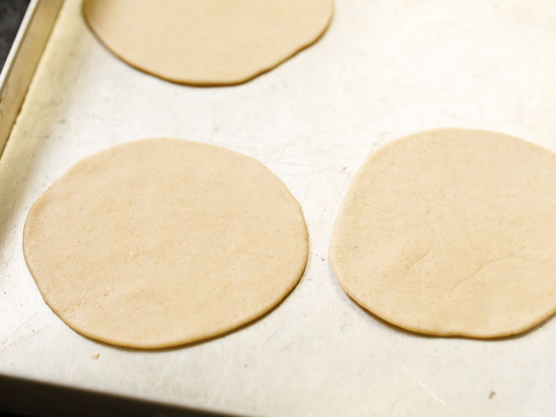 flat dough circles on a metal tray