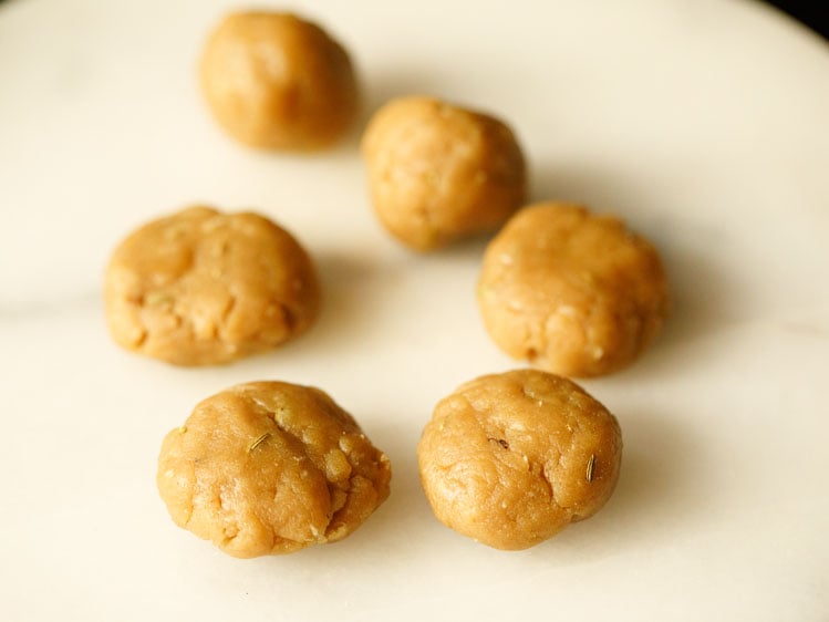 tablespoon size portions of thekua dough on a white surface