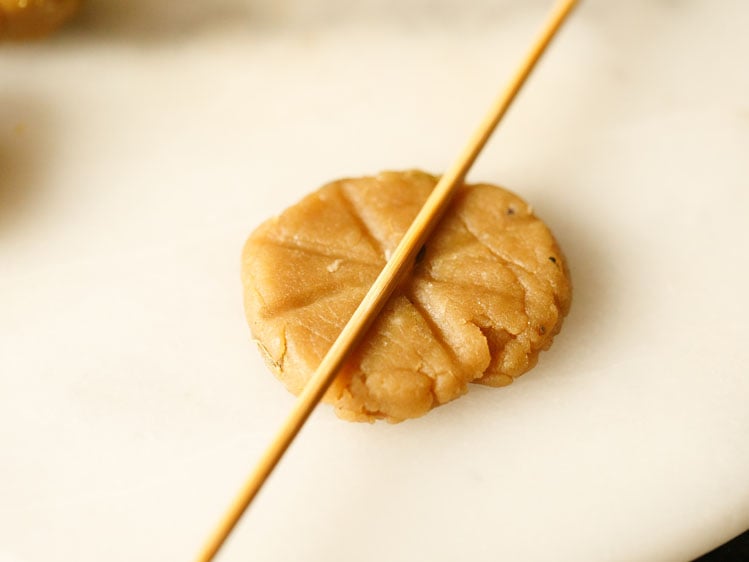 bamboo skewer making imprints on flattened piece of thekua dough