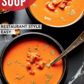 homemade rustic tomato soup from scratch in a black wooden bowl with a silver spoon topped with croutons and parsley with a bold font of "Tomato Soup" listed on photo