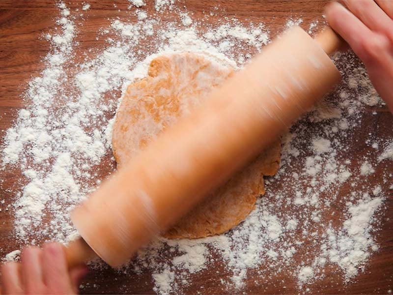 dough being rolled with a rolling pie