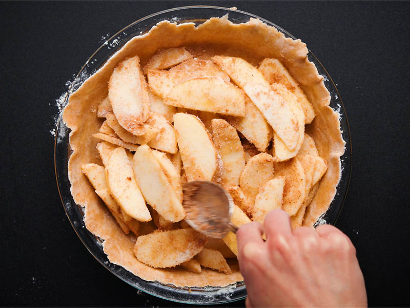 pie crust being topped with apple pie filling