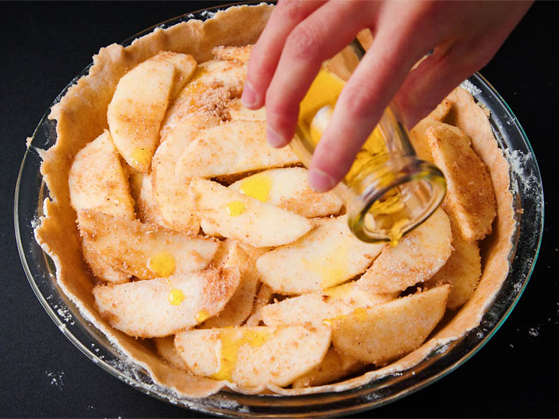 olive oil being sprinkled on apple pie filling