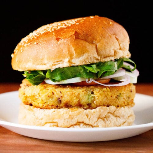 burger made with veggie patty, topped with onion, cucumber and lettuce on a white plate