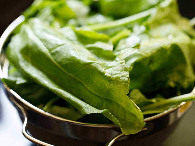 fresh spinach leaves in a silver colander