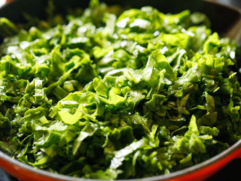 fresh shredded spinach added to the skillet with the cooked onions and garlic