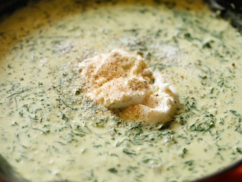 salt, pepper and nutmeg on top of unmelted piece of cream cheese floating in creamy spinach mix