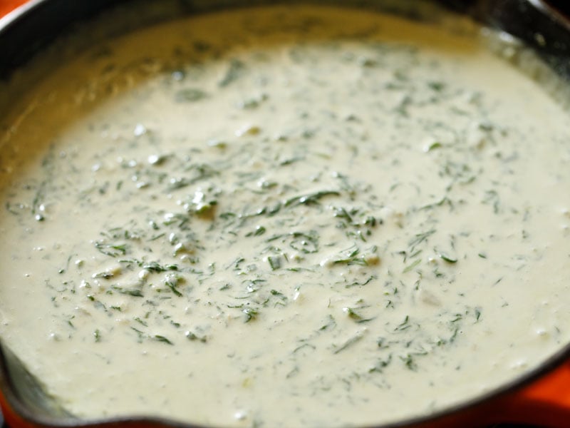 completed creamed spinach recipe in a red/orange enameled skillet on the stovetop