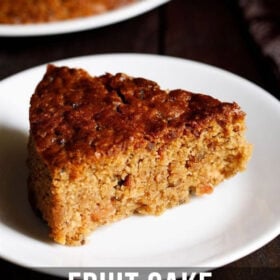 a thick triangular slice of eggless fruit cake in a white plate