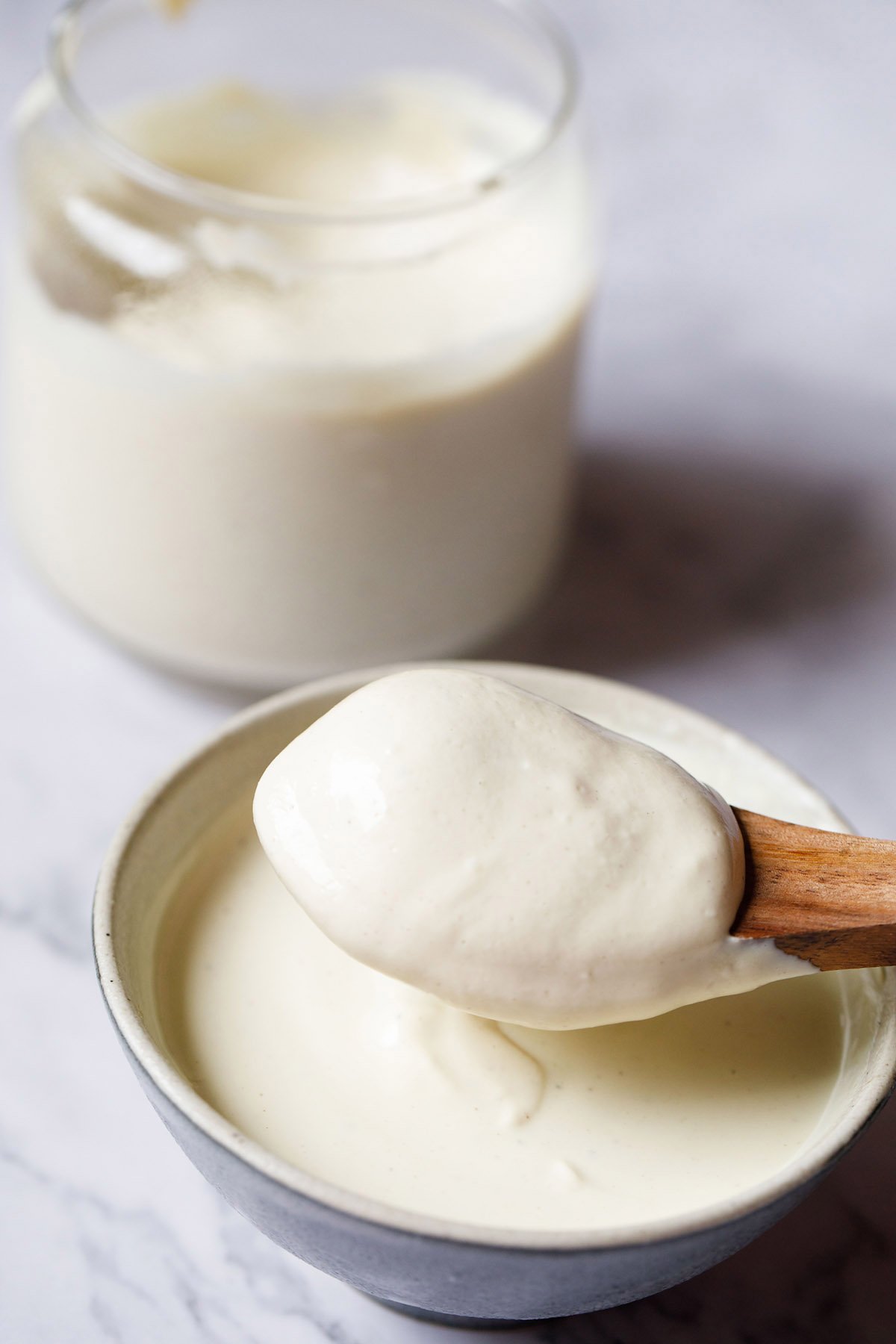 eggless mayonnaise in a bowl with a small wooden spoon showing the thick consistency