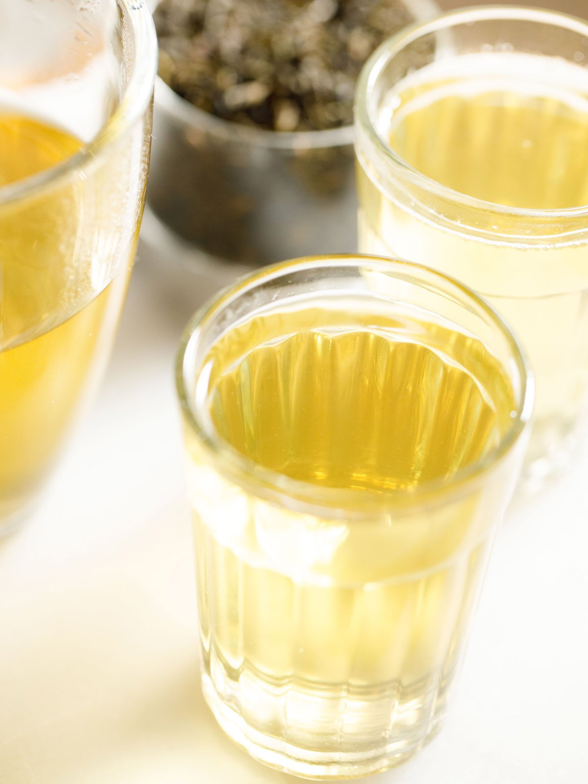 green tea in a transparent glass with a glass mug sideways on a white marble board