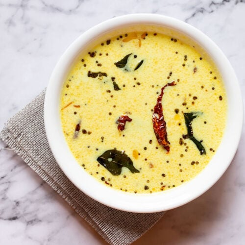 kerala moru curry in a white bowl on a white marble table