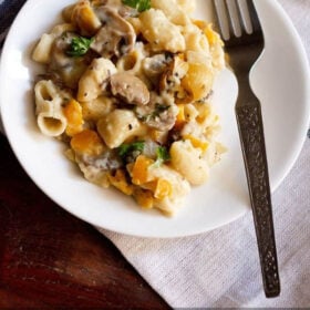 mushroom pasta served in a white plate with a steel fork at the side