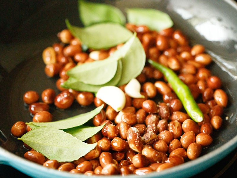 curry leaves, garlic cloves and green chillies added to the roasted peanuts