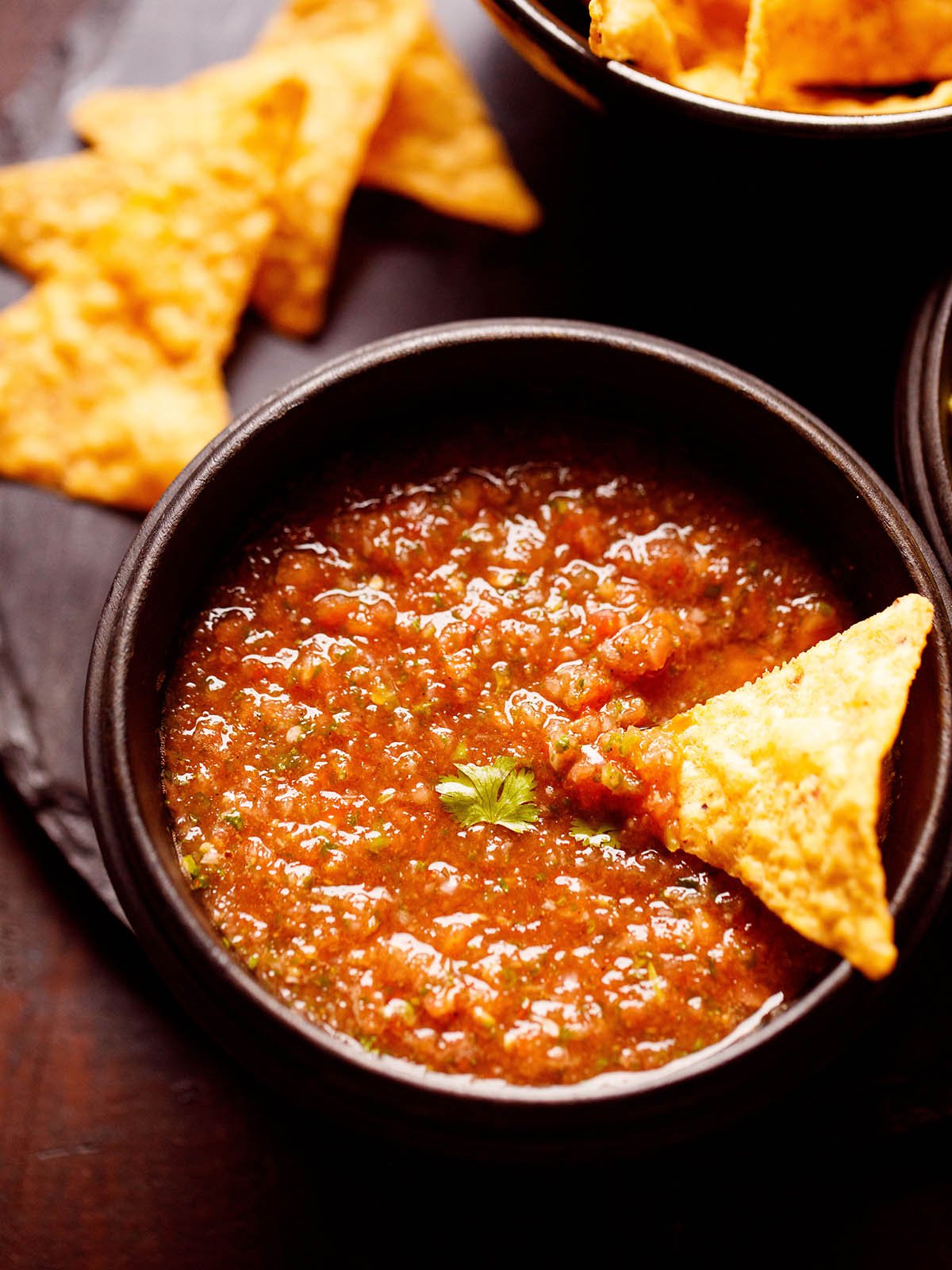 spicy tomato salsa with a nacho chip dipped in it 