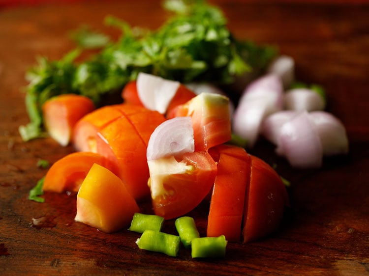 chopped, tomatoes, onion, cilantro, green chillies on a chopping board