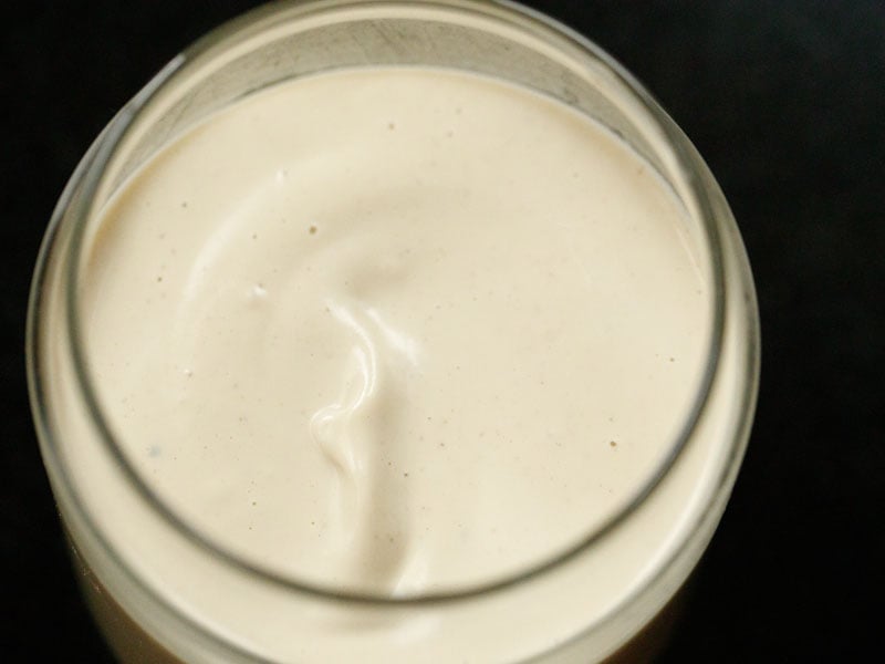 glass jar filled with vegan mayo on a black background