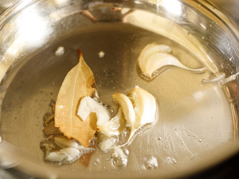 hoja de laurel, ajo salteado en aceite en una olla para hacer caldo de verduras