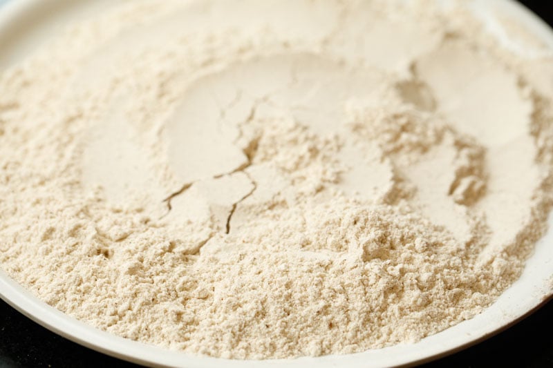 flour spread out on white plate to make apple cake