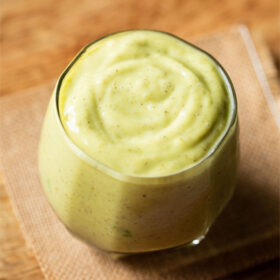 avocado shake in a glass on jute napkin on light brown wooden board