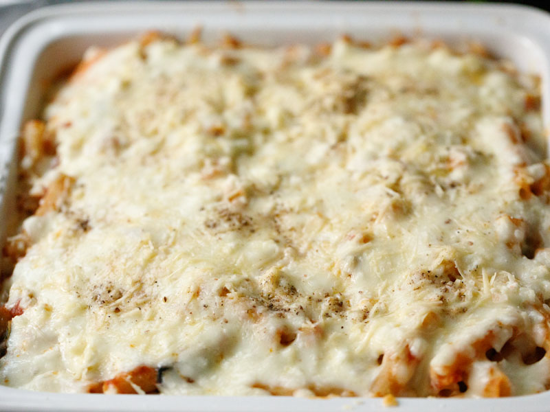 melted cheese atop baked ziti with ricotta in a white casserole dish after baking