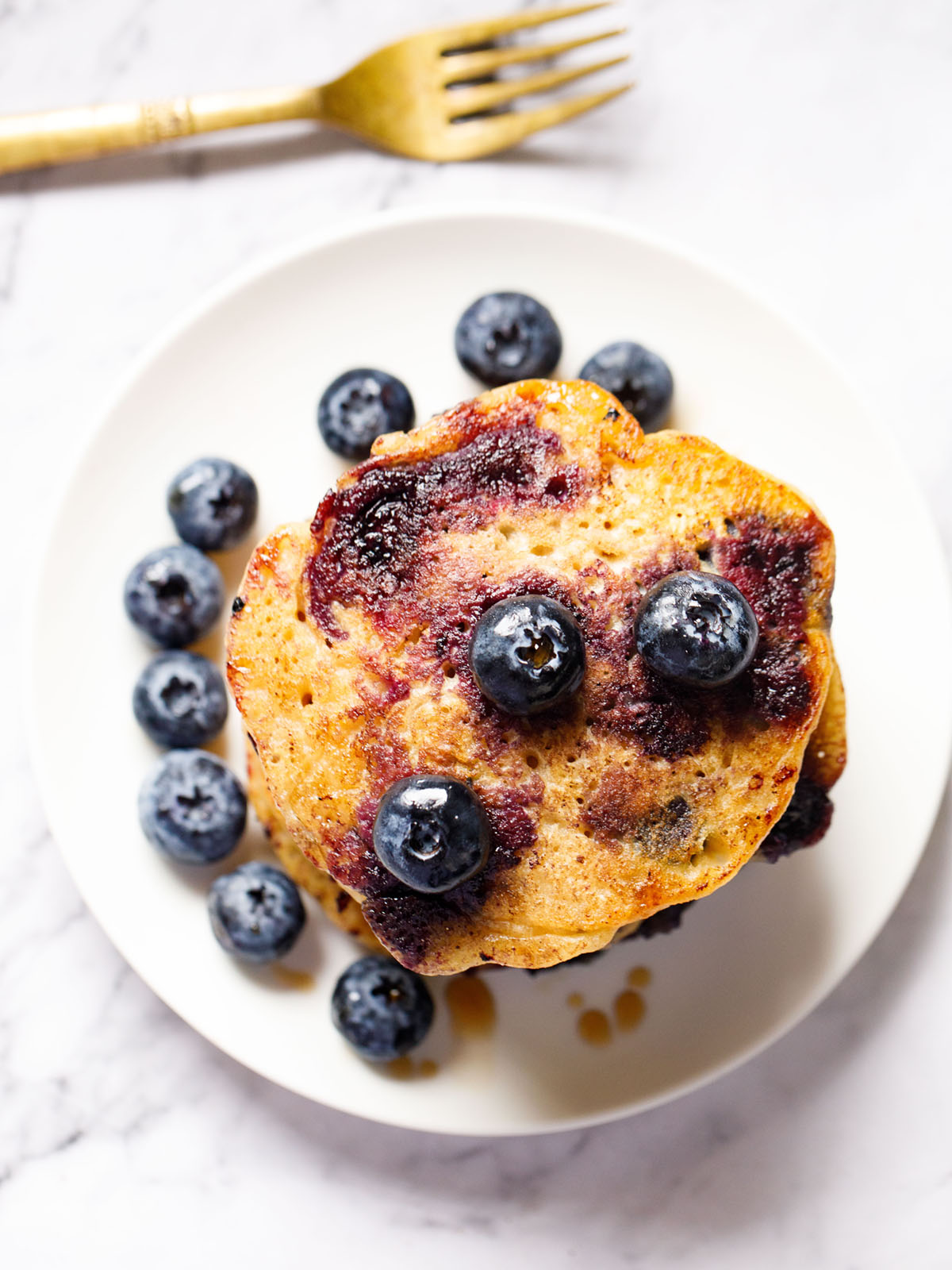 top shot of blueberry pancakes with blueberries in a white plate.