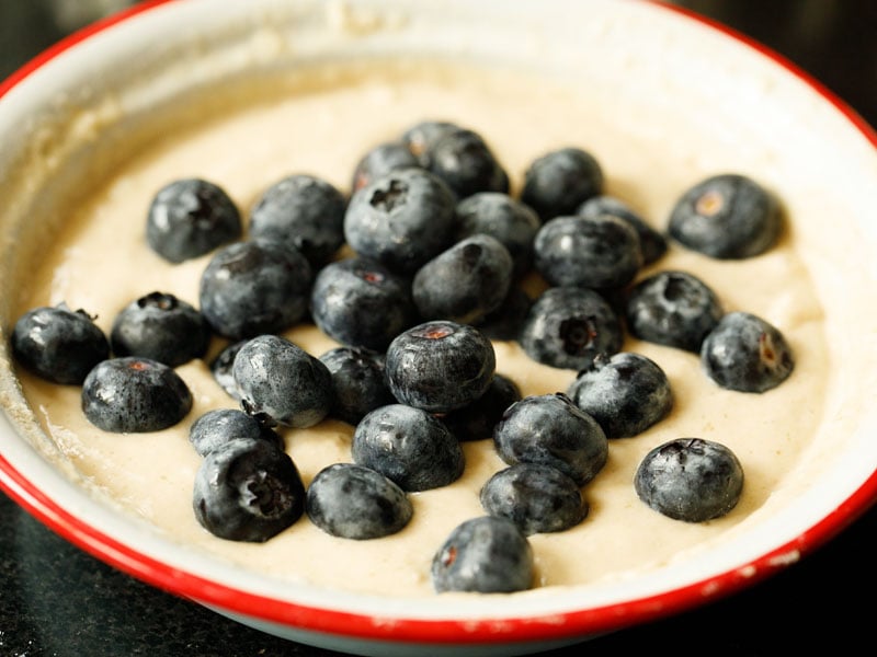fresh blueerries atop pancake batter in mixing bowl
