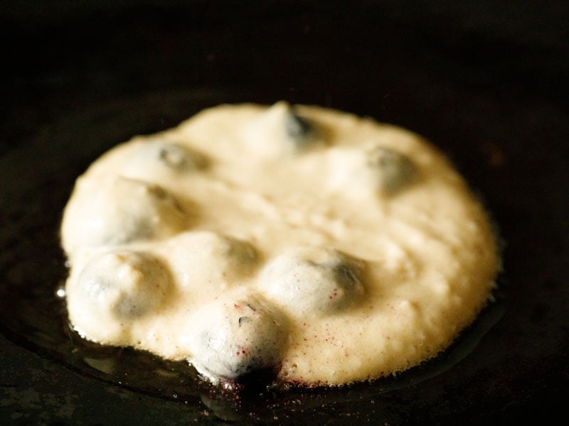 close up shot of vegan blueberry pancake cooking on a skillet with a bit of oil