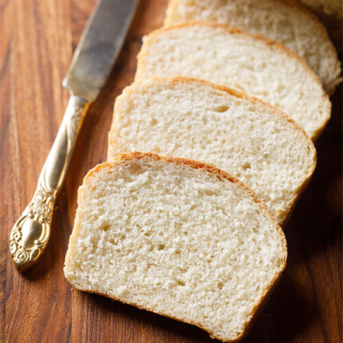 bread slices placed on top of each other with an antique butter knife on a brown wooden board