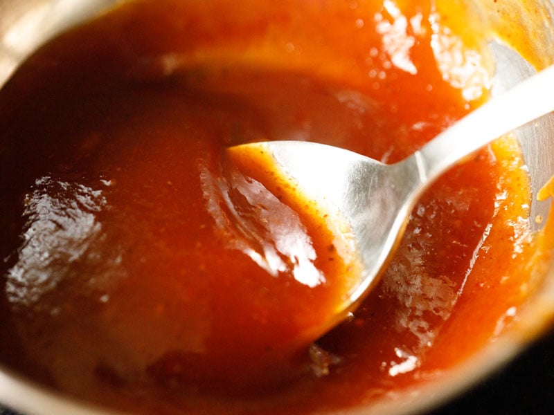 tamarind chutney in a bowl with a spoon inside