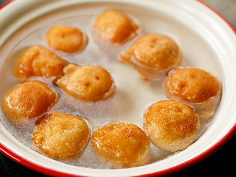 vada soaking in water in a red rimmed white bowl