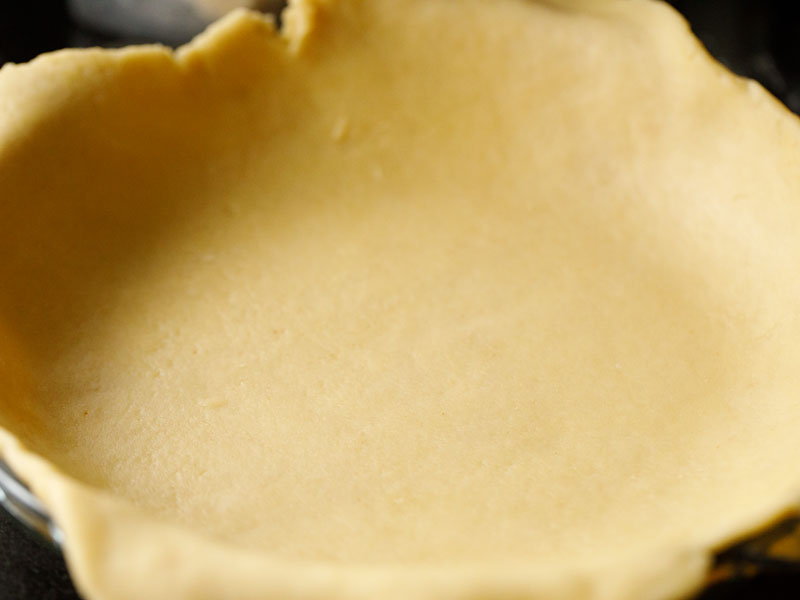 pie crust that has been rolled out and laid into a pie dish prior to trimming 