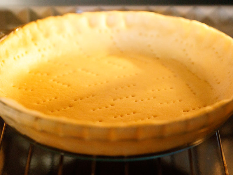 empty pie shell in a clear pie dish in the oven to par bake