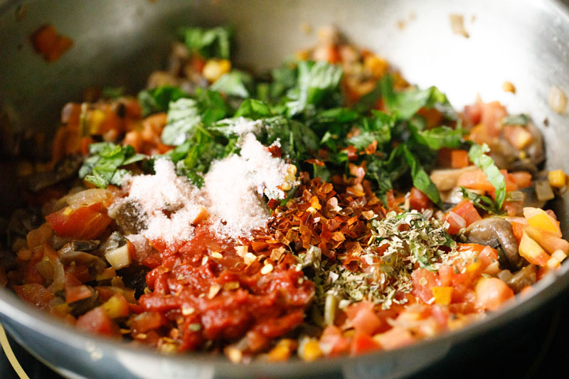 herbs, spices, tomato paste and salt added on top of sautéed tomatoes